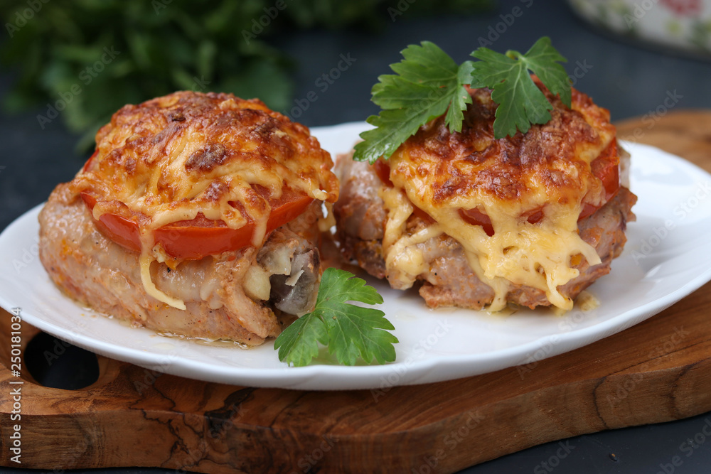Chicken thighs with tomatoes and cheese arranged in a plate on a wooden board