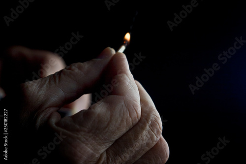 Burning match in the hand of an old grandmother