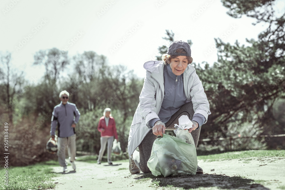 Fashionable old lady in grey hat helping other elderly people