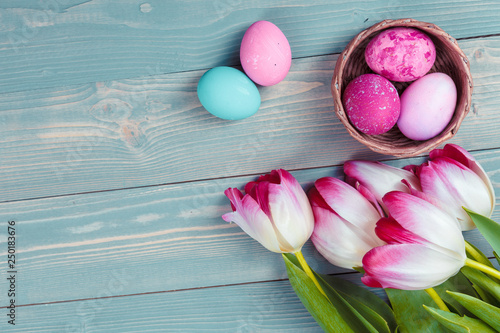 Easter eggs with tulips on blue wooden background