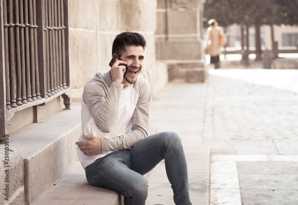 Young attractive happy man talking on smart phone in european city