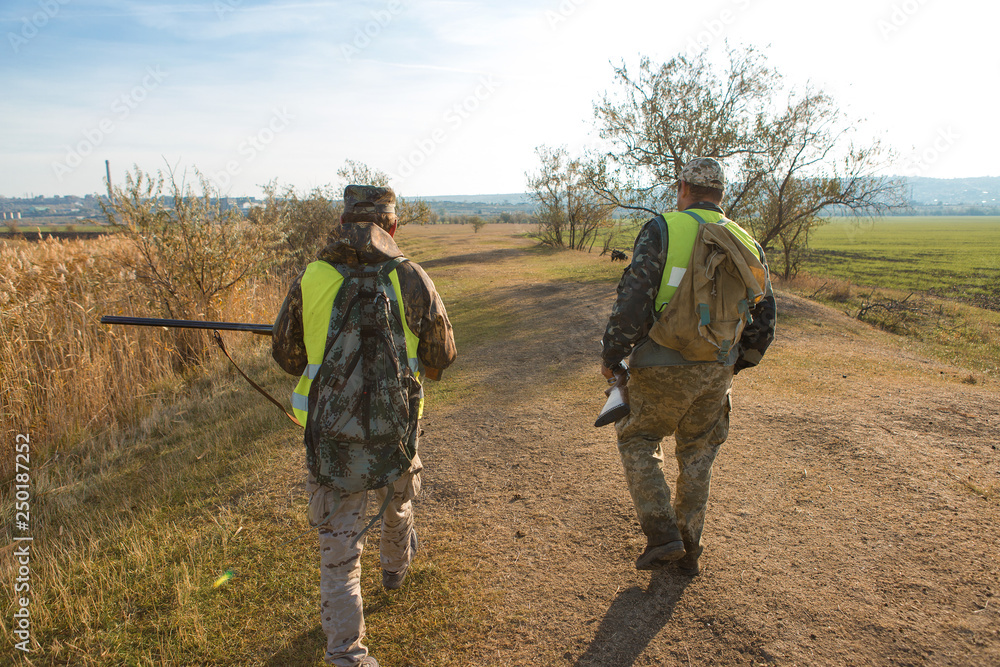 Hunter with a gun and a dog go on the first snow in the steppe, Hunting pheasant in a reflective vest Hunter with a gun and a dog go on the first snow in the steppe, Hunting pheasant in a reflective vest