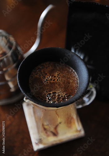 Coffee blooming in porous ceramic paperless dripper filter. Close up. Alternative manual brewing. Gooseneck kettle photo