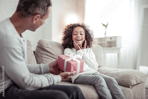Happy little girl receiving a nice gift from her father