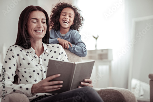Beautiful nice mother reading a book together with a daughter