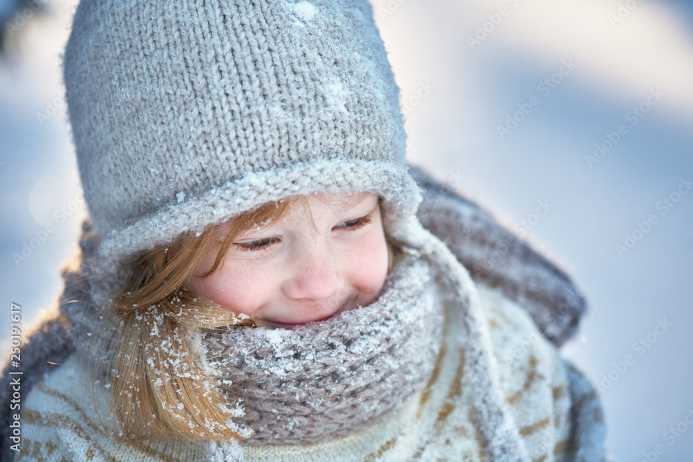 Little cheerful girl in a snow-covered hat, scarf and sweater. Snow around Little cheerful girl in a snow-covered hat, scarf and sweater. Snow around
