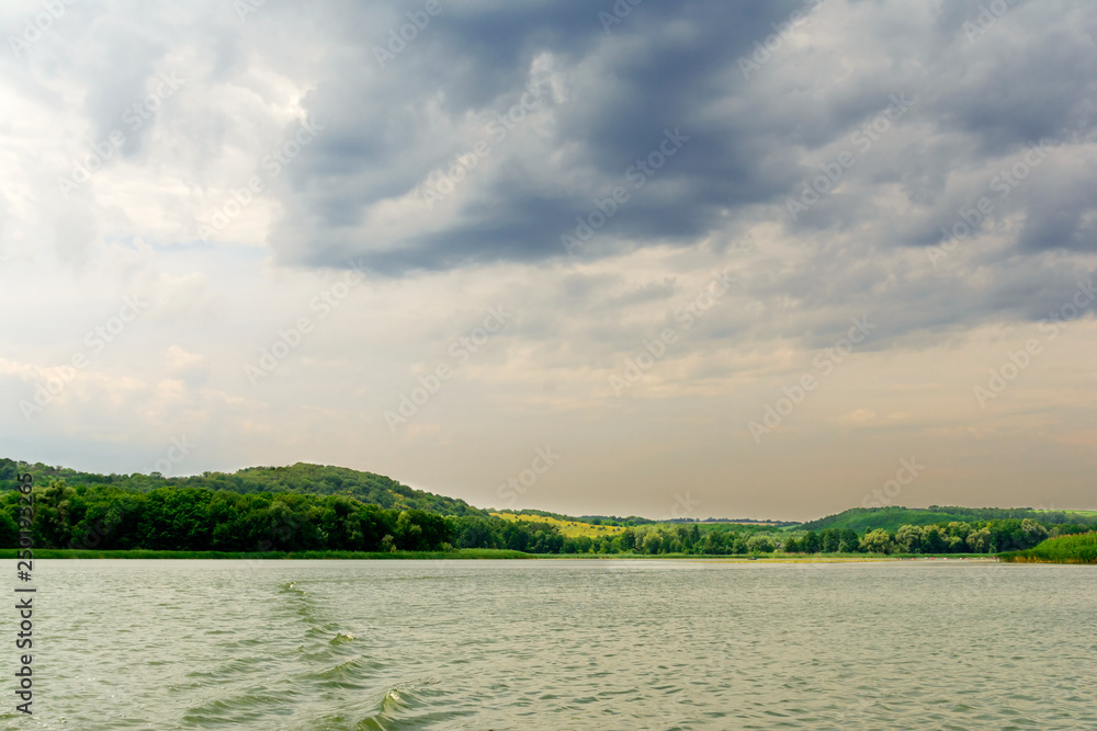 landscape green meadow , wide river and cloudy sky before the rain