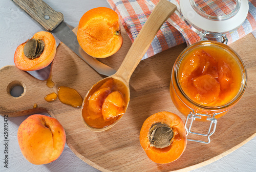 Apricot jam and apricot slices on a cutting board. photo