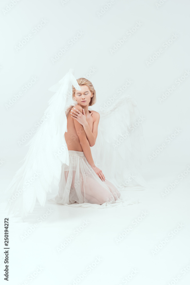beautiful young woman with angel wings sitting and posing isolated on white beautiful young woman with angel wings sitting and posing isolated on white