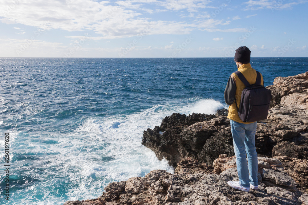 man tourist in yellow vest with backpack on rock cliff in Malta man tourist in yellow vest with backpack on rock cliff in Malta