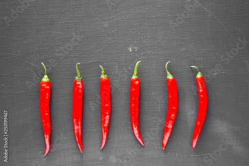 Hot red chili peppers on black background, top view. From above, overhead, flat lay. Copy space.