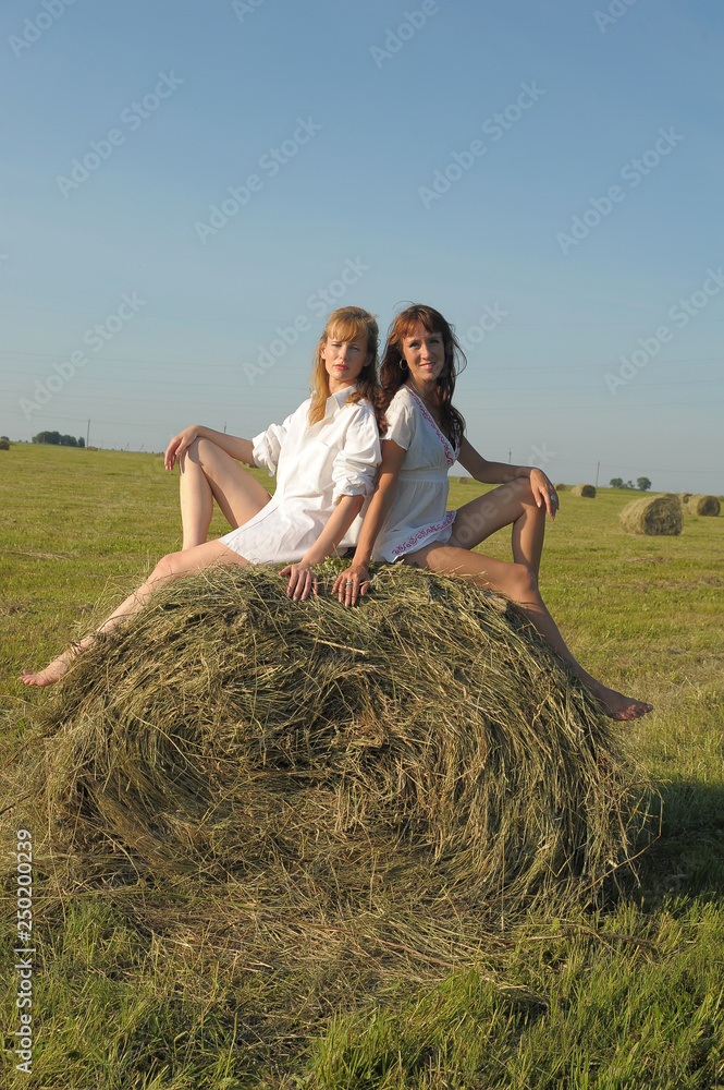 two women in white shirts in a field two women in white shirts in a field