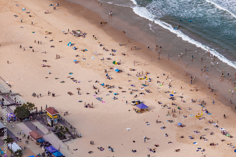 Aerial view of people on ocean beach - sunbathing and swimming