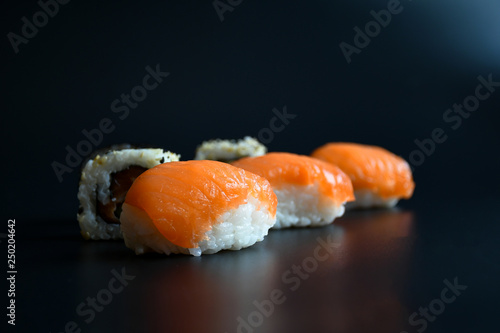 Close up  sushi with various ingrediant as salmon, tuna, avocado,sesame on black background. Sushi is a deliciousJapanese dish, rice cooked with vinagre and top with fish, or vegetable . photo