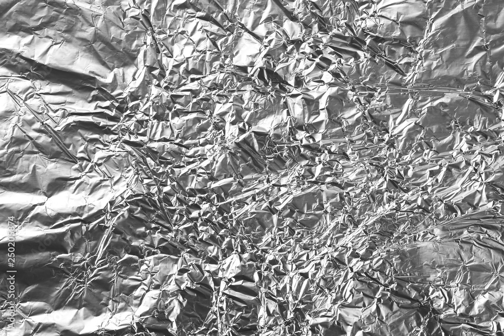Fototapeta premium Crumpled silver aluminum foil background, abstract texture
