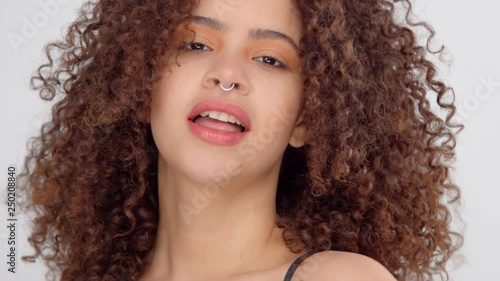 happu fun mixed race model with freckles havig fun making faces to a camera showing tongue and touching her curly hair photo