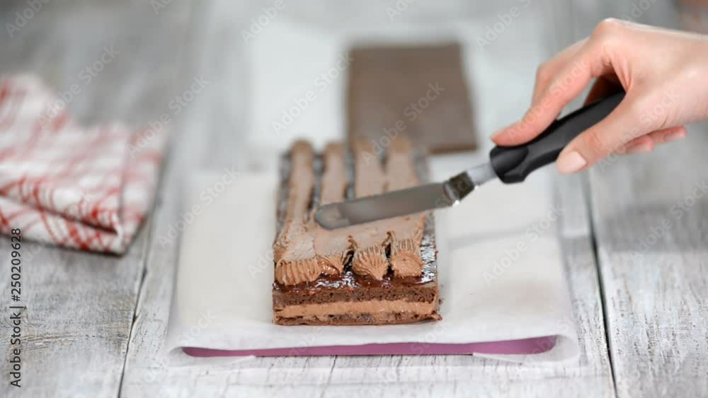Woman's hand spreading chocolate cream on chocolate sponge cake. Woman's hand spreading chocolate cream on chocolate sponge cake.
