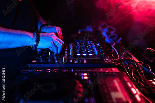 Close up of DJ hands controlling a music table in a night club.