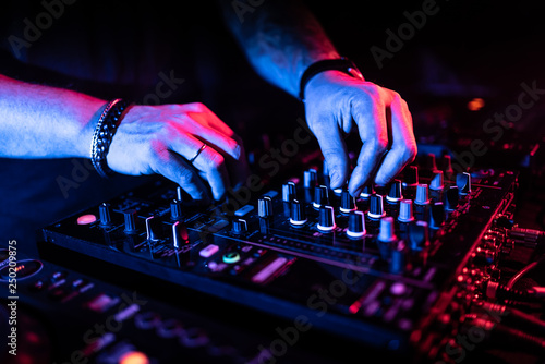 Close up of DJ hands controlling a music table in a night club.