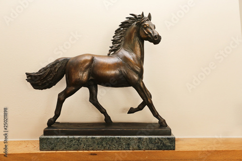 Bronze equine sculpture of beautiful horse against blurred riding hall