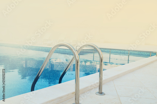 metal railings and swimming pool in the foggy summer morning, with space for text © Romo Lomo