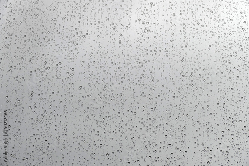 texture of rain drops on window glass over blur and cloudy sky background