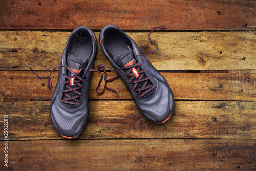 Top view of gray and orange trainers on a wooden background.