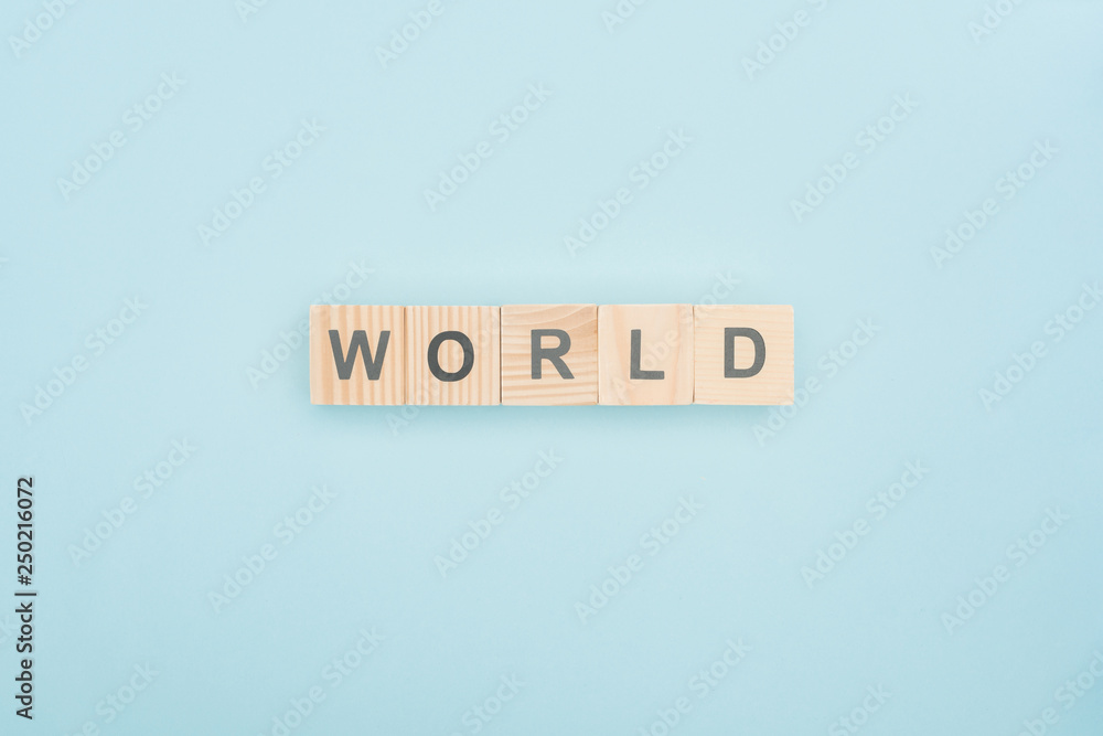 top view of world lettering made of wooden blocks on blue background top view of world lettering made of wooden blocks on blue background