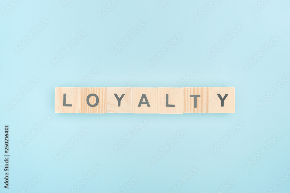 top view of loyalty lettering made of wooden cubes on blue background top view of loyalty lettering made of wooden cubes on blue background