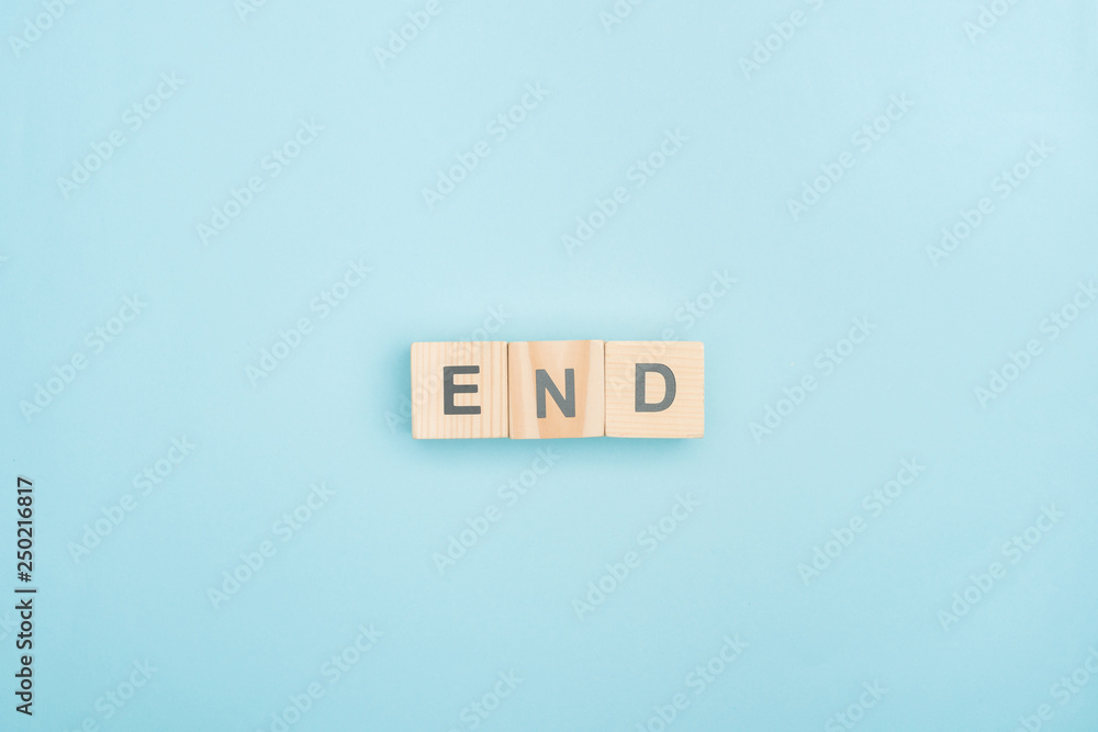 top view of end lettering made of wooden cubes on blue background top view of end lettering made of wooden cubes on blue background