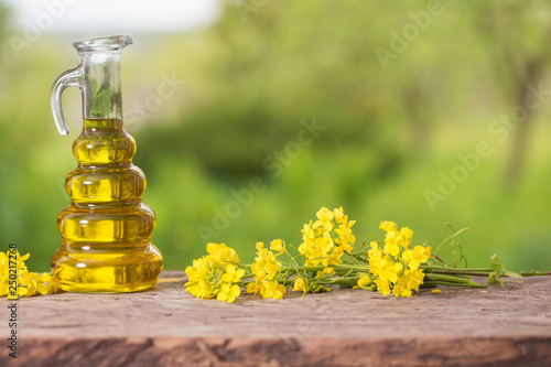 rapeseed oil (canola) and rape flowers on wooden table