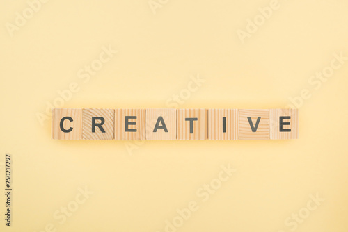 top view of creative lettering made of wooden cubes on yellow background