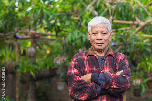 Portrait of elderly man standing in home garden.