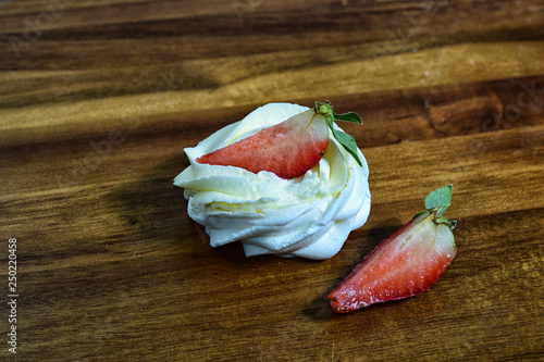 pavlova merengue dessert on wooden table. this is dessert made of round merengue and strawberry. homemade, delicious. tasty and organic. sweet dessert for any time of year and any weather.