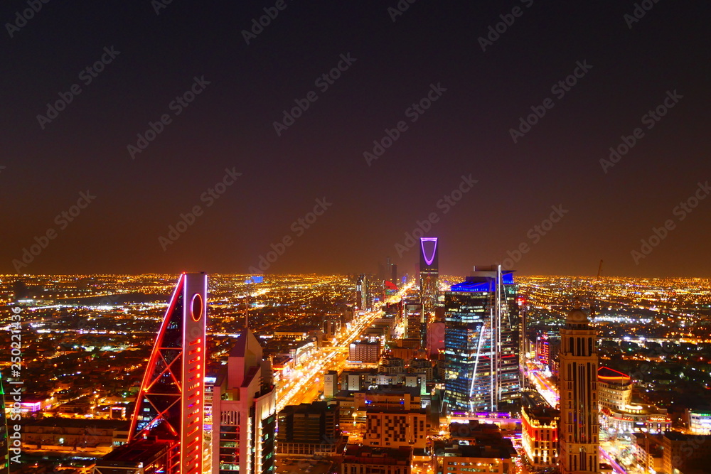 Fototapeta premium Panorama view to the skyline of Riyadh by night, with skyscrapers in the background and busy traffic on the streets of Riyadh, the capital of Saudi Arabia