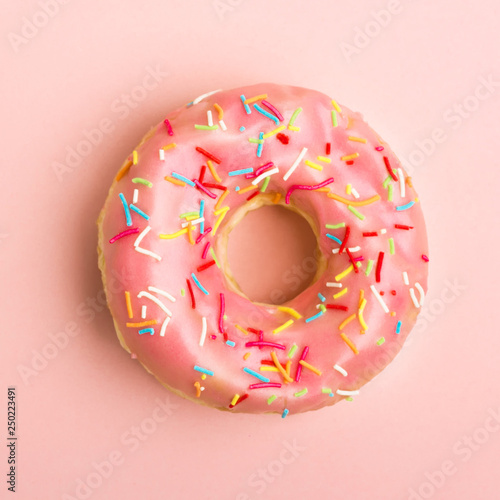 Donut decorated with sprinkles on coral background. Living coral color. Flat lay. Top view