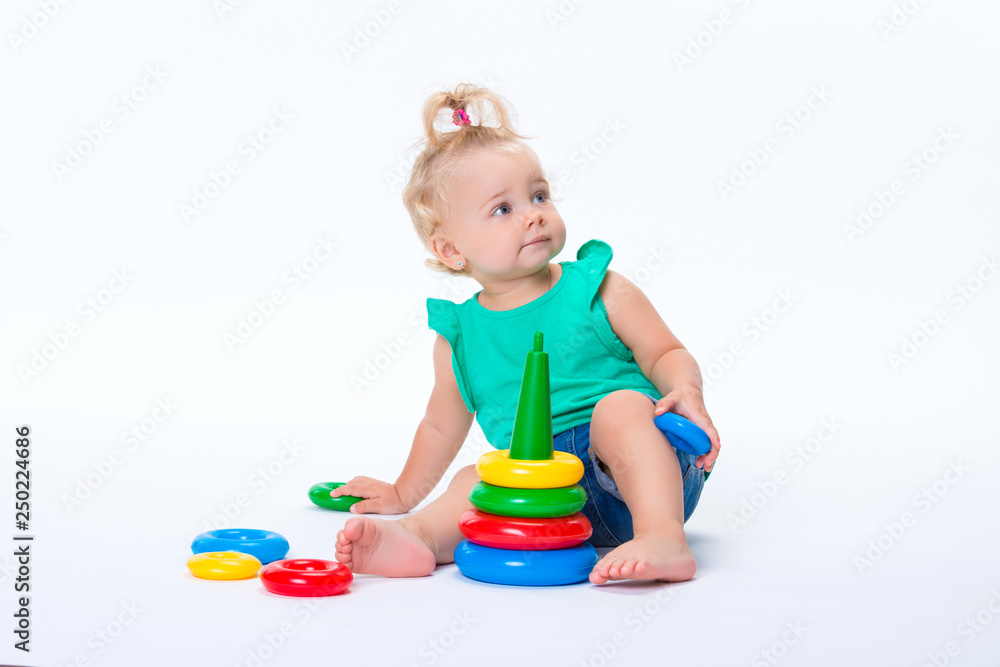 Cute kid blonde girl playing with color pyramid toy isolated on white background. Happy childhood and pre-school development of children Cute kid blonde girl playing with color pyramid toy isolated on white background. Happy childhood and pre-school development of children