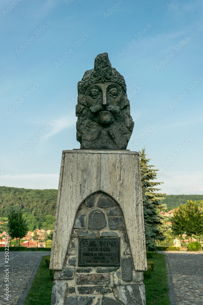 Fototapeta premium Sighisoara, Transylvania region, Romania - June 10, 2018: Ancient statue of Vlad Tepes and an old Dominican monastery