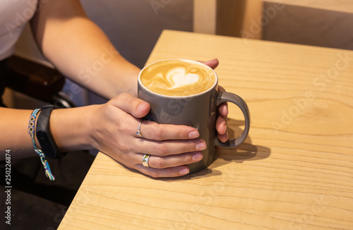 Girl's hands holding a cup of coffee, ripped jeans. Fashion manicur photo