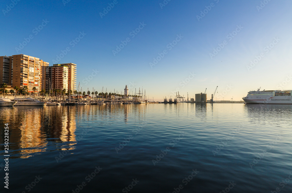 Sunny skyline reflection on the water of the port while ship is leaving