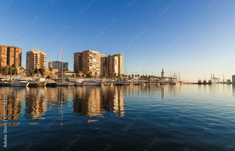 Sunny skyline reflection on the water of the port of malaga