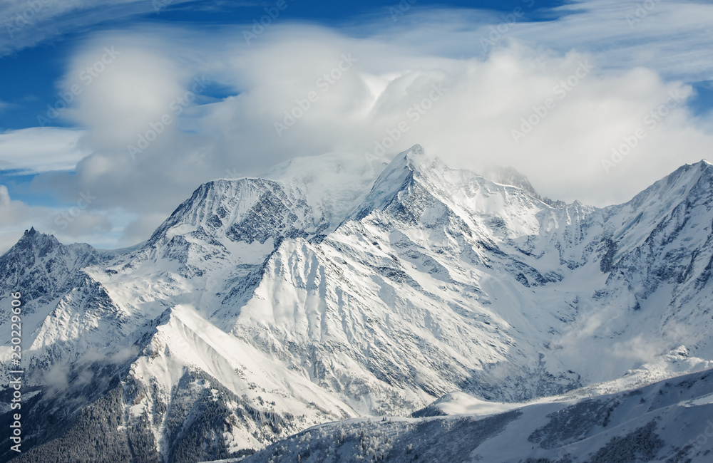 The snow-covered alpine mountain peaks in clouds