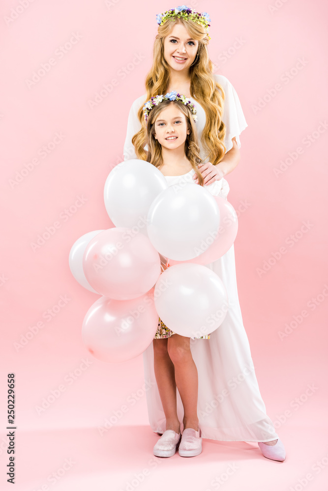 smiling child with festive air balloons standing near happy mother on pink background smiling child with festive air balloons standing near happy mother on pink background