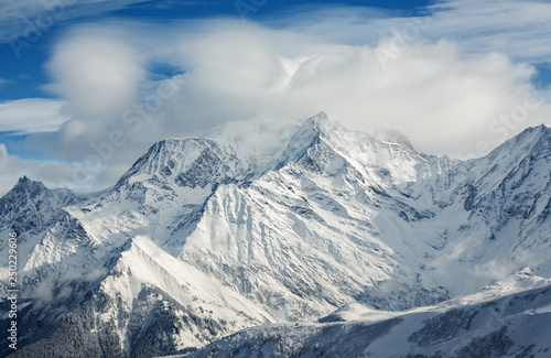 The snow-covered alpine mountain peaks in clouds