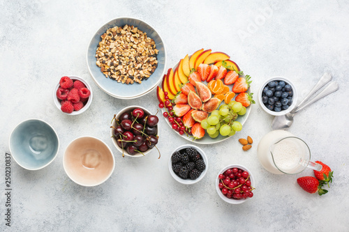 Raw vegan gluten and grain free paleo granola or muesli made from nuts. Fruit berries platter, strawberries blueberries raspberries peach figs red currant, above view, selective focus