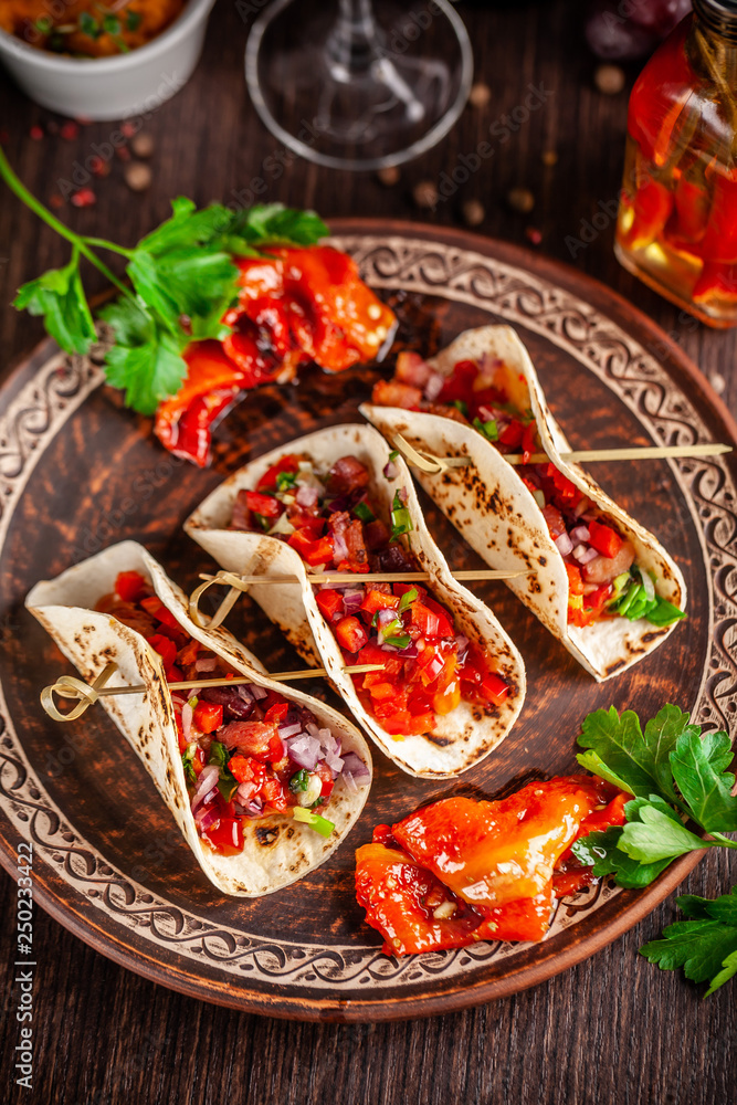 Concept of Mexican cuisine. Mexican appetizer Tacos with vegetables, beans, paprika, chilli peppers on fried unleavened bread cakes. Taco for veterinarians. Background image.