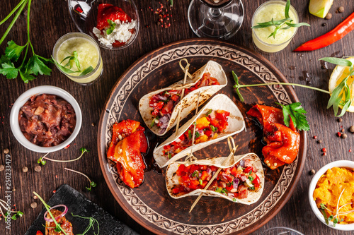 The concept of Mexican cuisine. Mexican food and snacks on a wooden table. Taco, sorbet, tartar, glass and bottle of red wine. Background image. Top view, copy space