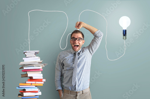 Bilde på lerret Young man smiles and holds a bright light bulb on the wire