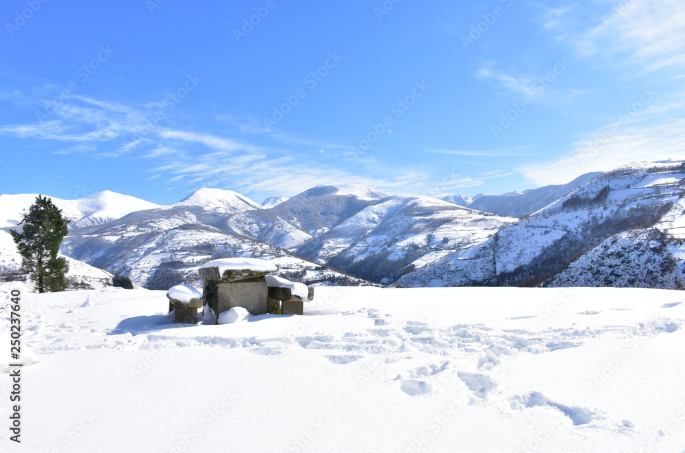 Winter landscape with mountains and snowy viewpoint with stone table and benches. Ancares Region, Lugo Province, Spain