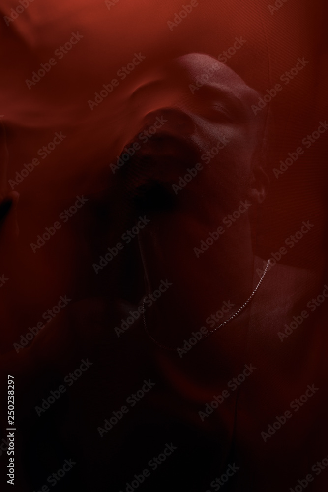 Art portrait of black man posing behind red fabric. Sensual. Art performance, acting. Art portrait of black man posing behind red fabric. Sensual. Art performance, acting.